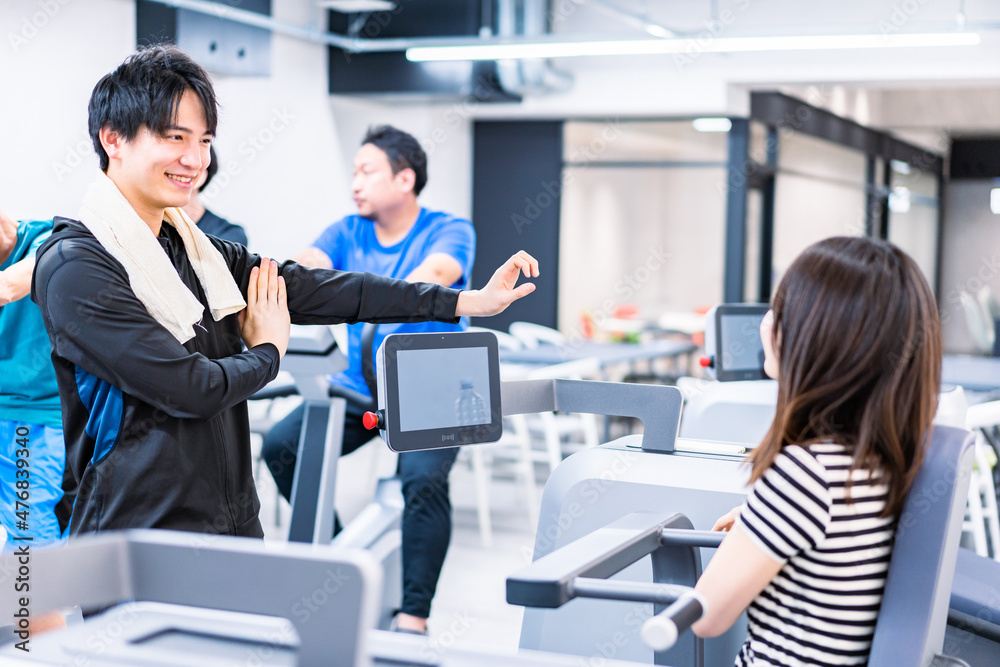 ジムでトレーナーの指導を受ける若い女性 ジムでトレーナーの指導を受ける若い女性