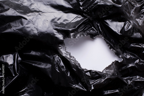 Torn, damaged black plastic foil, whole in a black plastic film