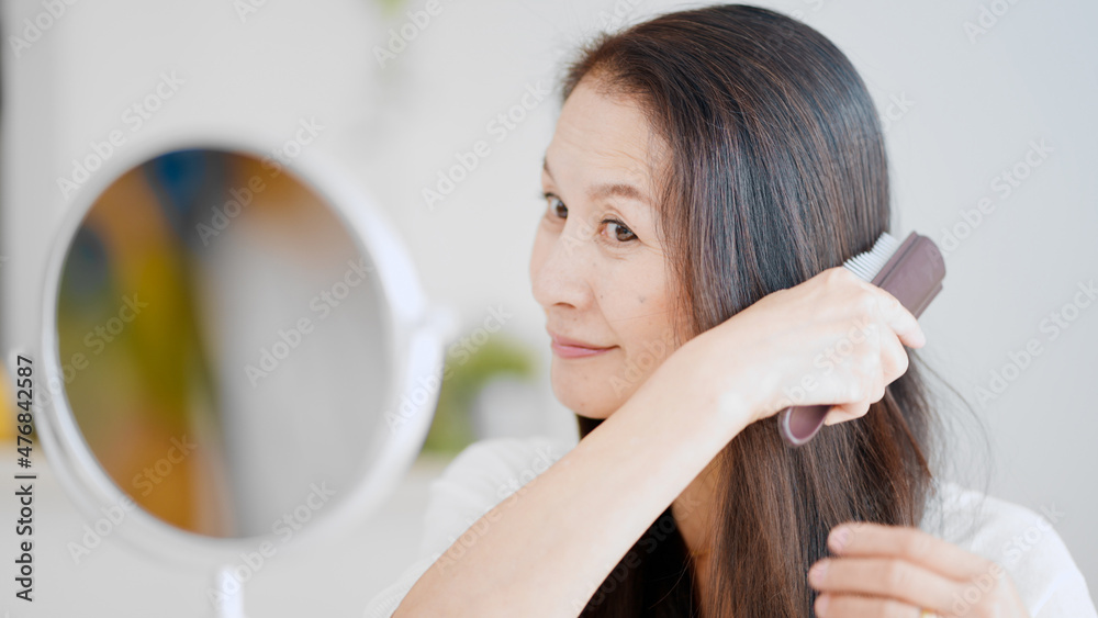 髪にブラシをかけるシニア女性
