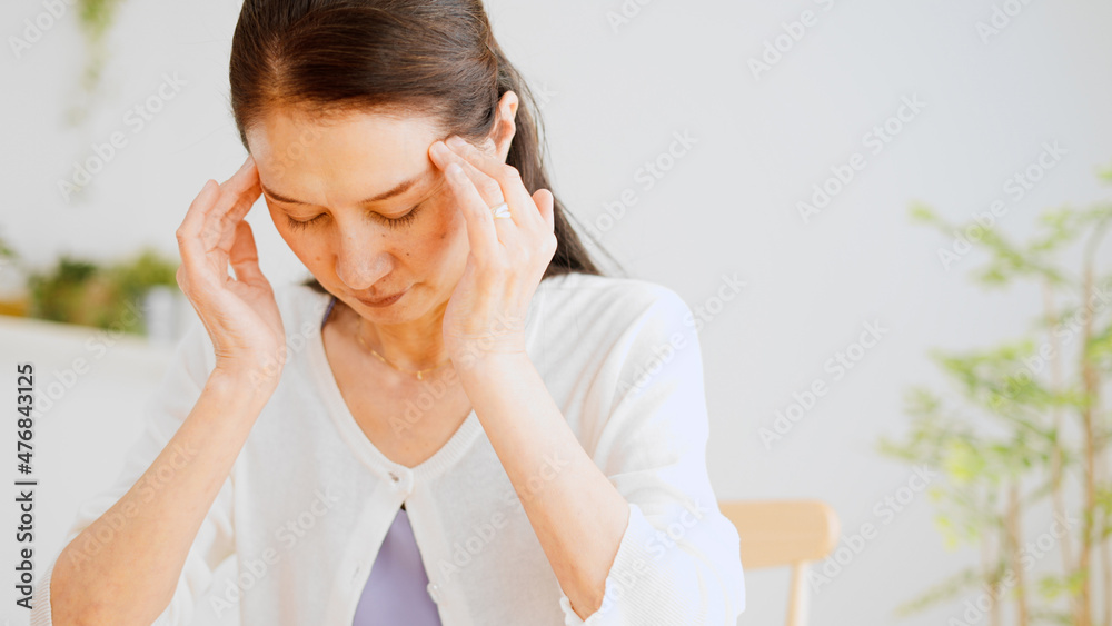 こめかみを押さえるシニア女性　頭痛