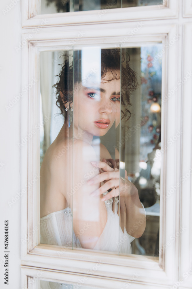 Beautiful curly-haired bride in a luxury wedding dress in a restaurant with wedding decor Beautiful curly-haired bride in a luxury wedding dress in a restaurant with wedding decor