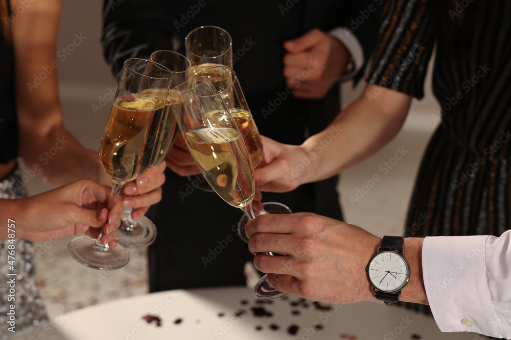 Friends clinking glasses of sparkling wine indoors, closeup. New Year celebration