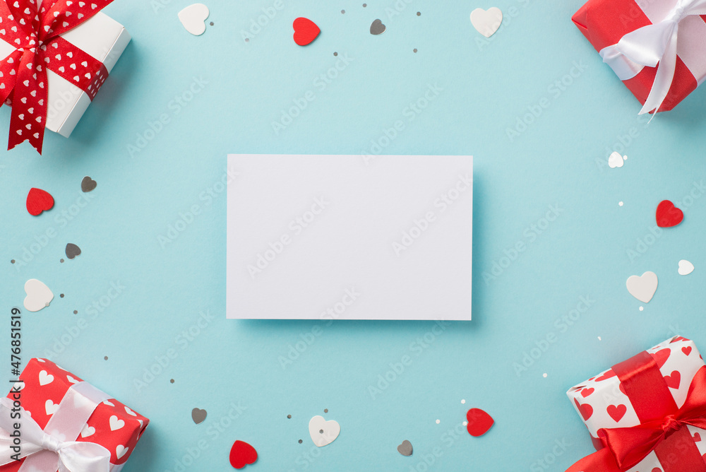 Top view photo of saint valentine's day decorations heart shaped confetti sequins gift boxes and paper sheet on isolated pastel blue background with blank space Top view photo of saint valentine's day decorations heart shaped confetti sequins gift boxes and paper sheet on isolated pastel blue background with blank space