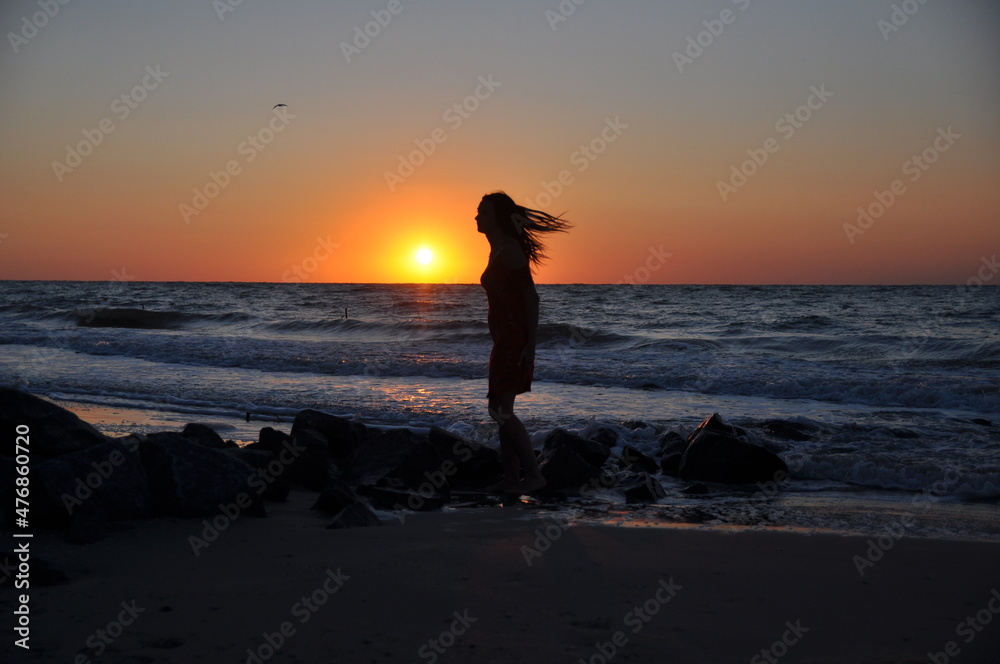 sea. the girl meets the dawn with the first rays of the sun