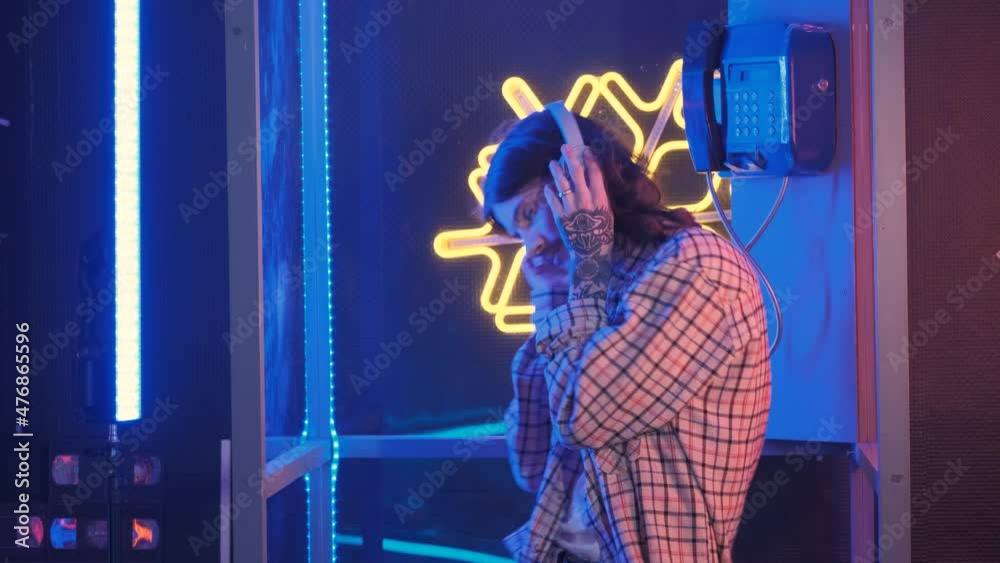 Millennial man in headphone dancing in old retro call box Millennial man in headphone dancing in old retro call box