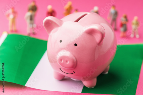 Piggy bank, Nigerian flag and plastic toy men on a colored background, the concept on the topic of income of the population of Nigeria
