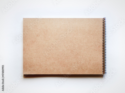螺旋綴じの茶色いスケッチブックの裏面。茶色いコピースペース。灰色背景で真上から撮影。
