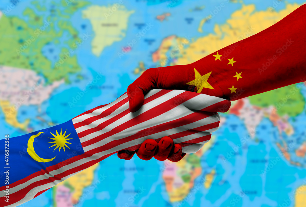 Naklejka premium Handshake between China and Malaysia flags painted on hands.With background of world map