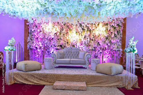 An elegantly staged traditional MOROCCAN style wedding with large sofa for the wedding couple to sit and receive blessings from the guests, surrounded by beautiful floral decor and candle light 