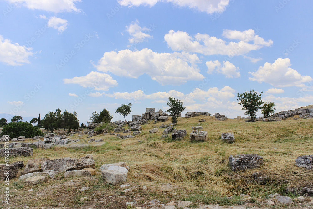 The remains of ancient stone ruins and a blue sky with white clouds. Landscape