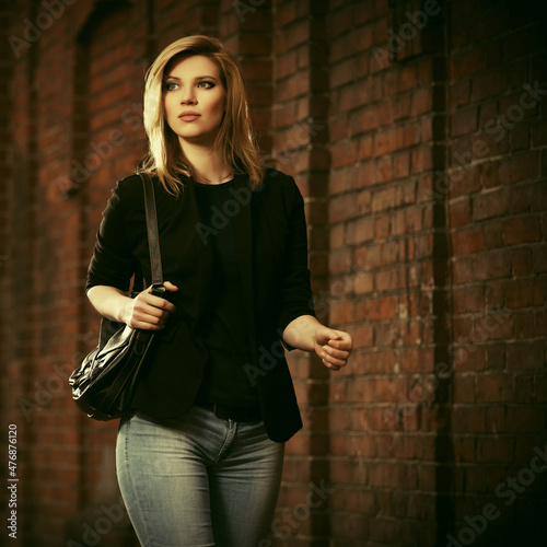 Young fashion blonde business woman in black blazer with handbag