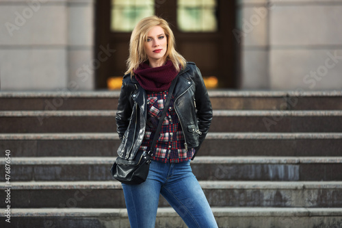 Young fashion blonde woman in black leather jacket and snood scarf