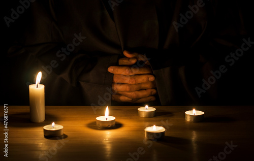 Hands of a monk praying in the dark with candlelights. photo