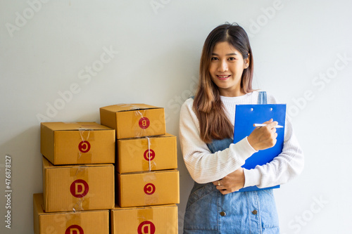 Happy business owner with past company sales, cropped image of woman standing looking at her own shipping box for delivery at online sales office, merchandising concept and modern businessman.