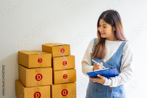 Happy business owner with past company sales, cropped image of woman standing looking at her own shipping box for delivery at online sales office, merchandising concept and modern businessman.