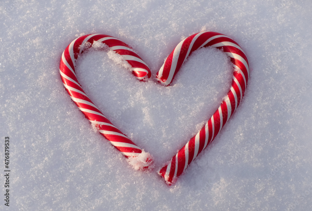 Christmas candy canes as heart on snow backround close-up