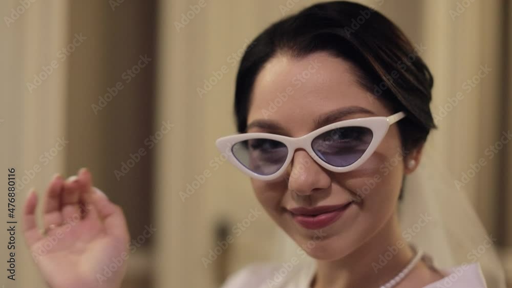 Close-up portrait of lovely stylish bride girl in sunglasses looking at camera, smiling. Wedding morning preparations before ceremony. Luxury bride with fashion hairstyle and makeup. Beautiful woman Close-up portrait of lovely stylish bride girl in sunglasses looking at camera, smiling. Wedding morning preparations before ceremony. Luxury bride with fashion hairstyle and makeup. Beautiful woman