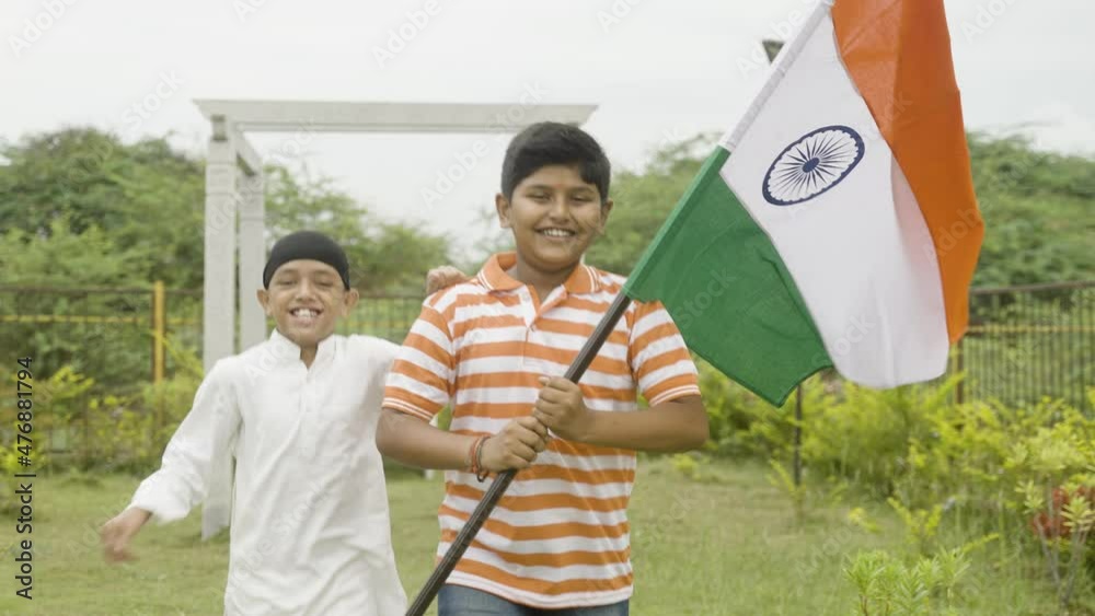 Multiethnic religious children running by holding Indian flag at park - concept of independence or republic day celebration, patriotism, democracy, unity in diversity and friendship.