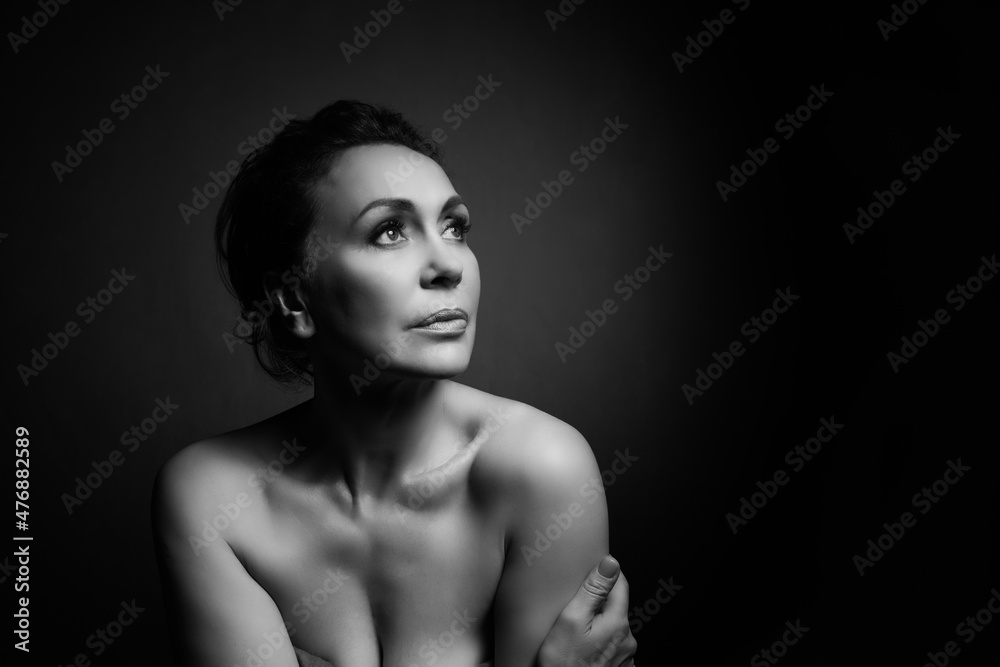 Portrait of a sensual fifty year old woman on grey studio background. Monochrome shot. Portrait of a sensual fifty year old woman on grey studio background. Monochrome shot.