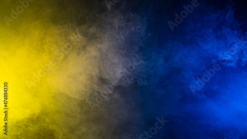 Yellow-blue smoke in neon light on black background.