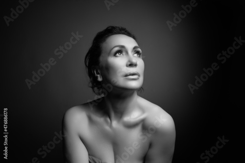 Portrait of a sensual fifty year old woman on grey studio background. Monochrome shot.