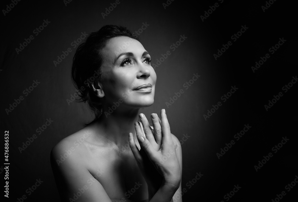 Portrait of a sensual fifty year old woman on grey studio background. Monochrome shot. Portrait of a sensual fifty year old woman on grey studio background. Monochrome shot.