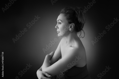 Portrait of a sensual fifty year old woman on grey studio background. Monochrome shot.