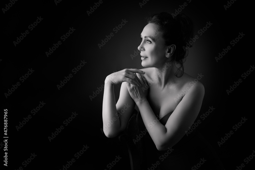 Portrait of a sensual fifty year old woman on grey studio background. Monochrome shot. Portrait of a sensual fifty year old woman on grey studio background. Monochrome shot.