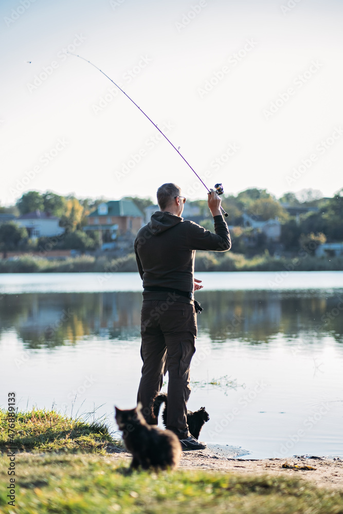 Fisherman with rod, spinning reel on the river bank. Fishing for