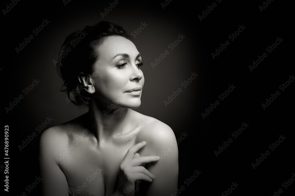 Portrait of a sensual fifty year old woman on grey studio background. Monochrome shot. Portrait of a sensual fifty year old woman on grey studio background. Monochrome shot.