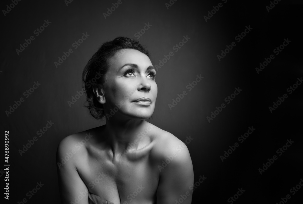 Portrait of a sensual fifty year old woman on grey studio background. Monochrome shot. Portrait of a sensual fifty year old woman on grey studio background. Monochrome shot.
