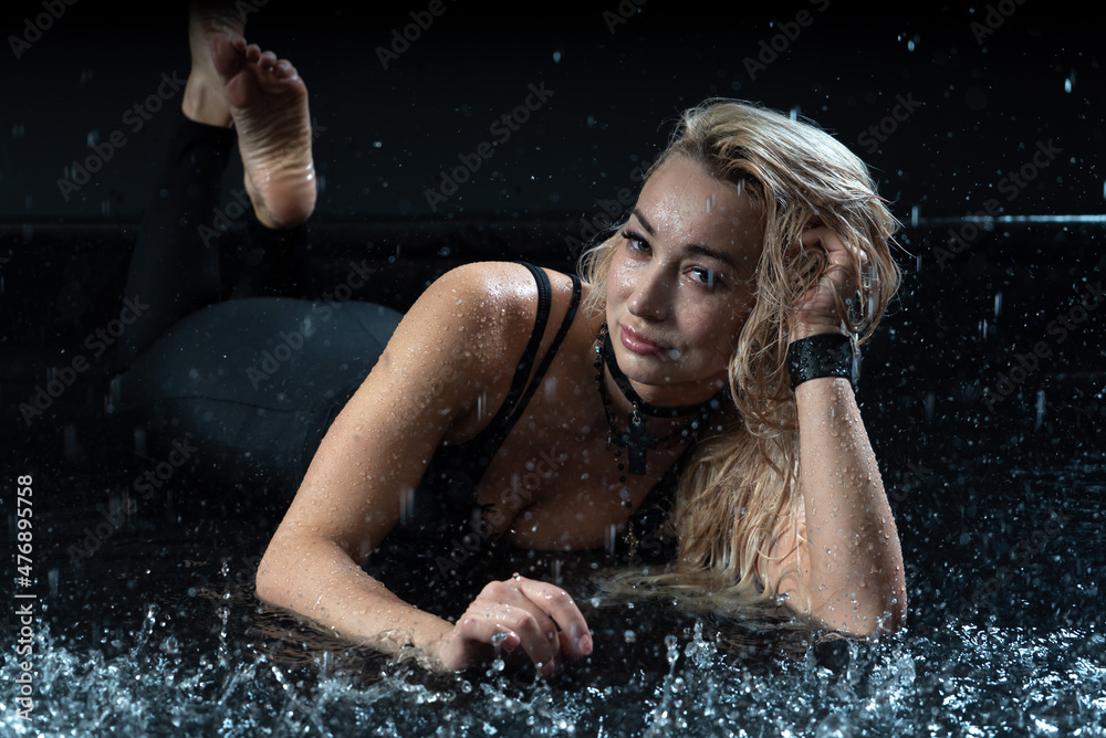 Obraz premium Sporty attractive woman in a swimsuit in the rain shooting in the studio. High quality photo