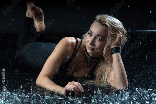 Sporty attractive woman in a swimsuit in the rain shooting in the studio. High quality photo