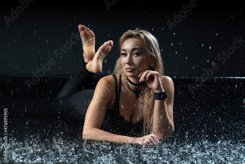 Sporty attractive woman in a swimsuit in the rain shooting in the studio. High quality photo