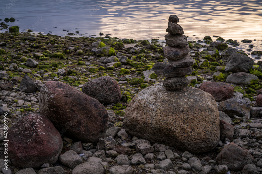 A cairn on a pebble beach with water in the background