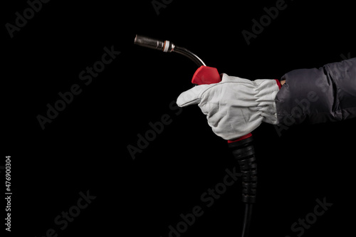 dark background. a human hand in white gloves holds a burner that feeds wire for welding parts.close-up.