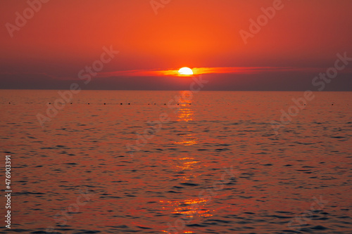 Beautiful landscape - beach on sunset -red and orange sky and sunlight reflecting on sea water.