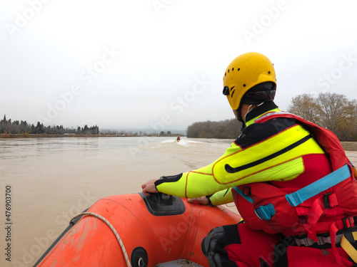 rescuer watches the river during a flood while riding in a boat