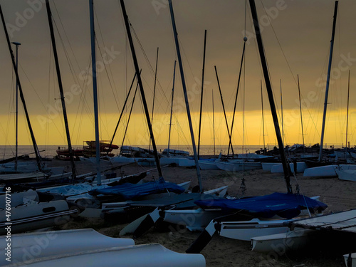 Yacht port on the beach over orange sunset with sailboats 