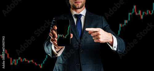 Fototapeta Naklejka Na Ścianę i Meble -  Investment concept. Businessman holding finance application for sell, buy and analysis profit dividend statistics. Investment business technology app on digital screen. Global currency background.