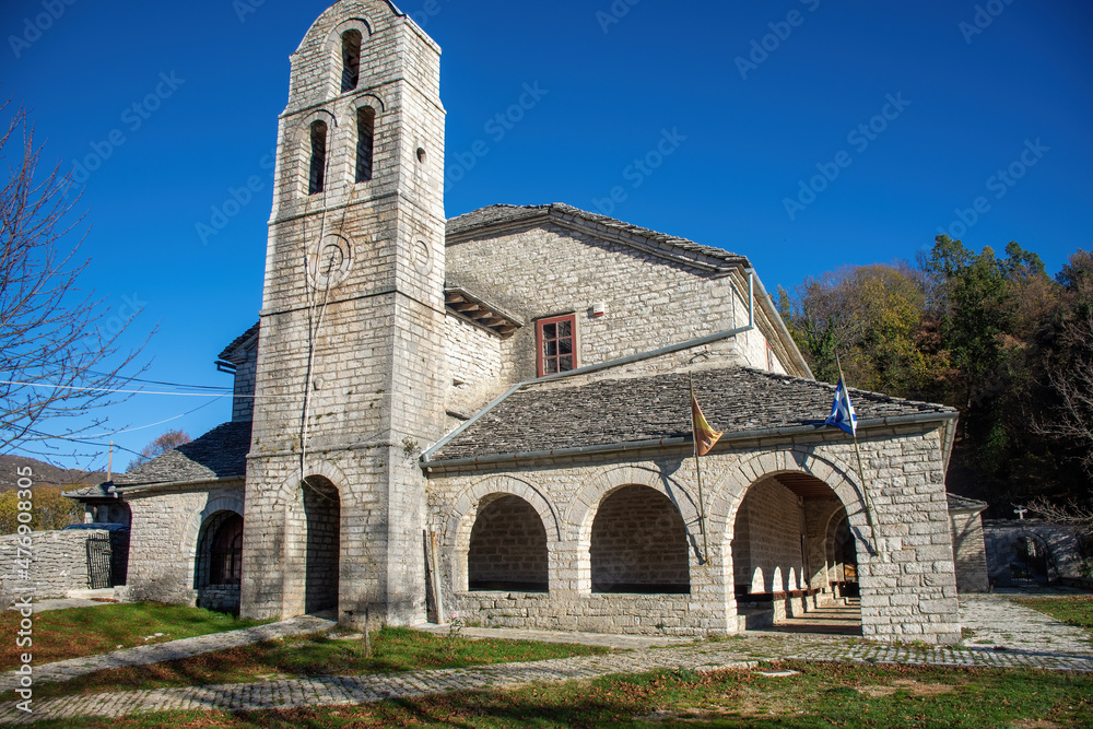 Traditional architecture with narrow stone road and Agios Athanasios stone built church during fall season in the stone village Monodendri central Zagori Greece