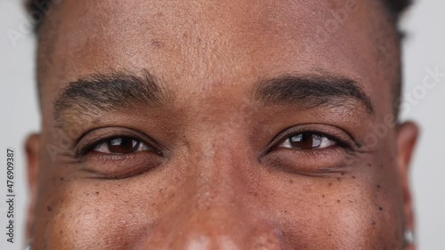 Close-up of the happy eyes of an African American looking into the camera, white background in the studio