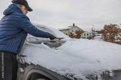 Close up view of man cleaning windshield from snow. Vehicle concept background. Sweden.