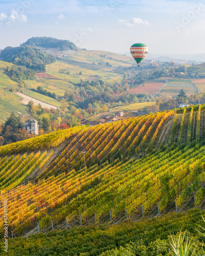 Hot air balloon over the beautiful hills and vineyards during fall season surrounding Barolo village. In the Langhe region, Cuneo, Piedmont, Italy. photo