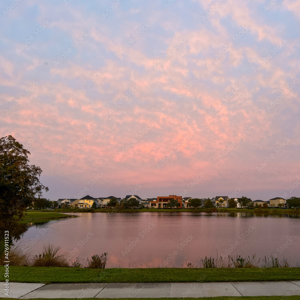 Obraz premium Beautiful pink, orange and blue sunset reflecting on a lake in a suburban neighborhood.