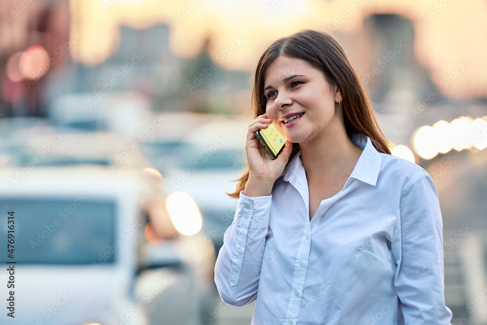 Smiling woman talks by handy on street with traffic. Smiling woman talks by handy on street with traffic.