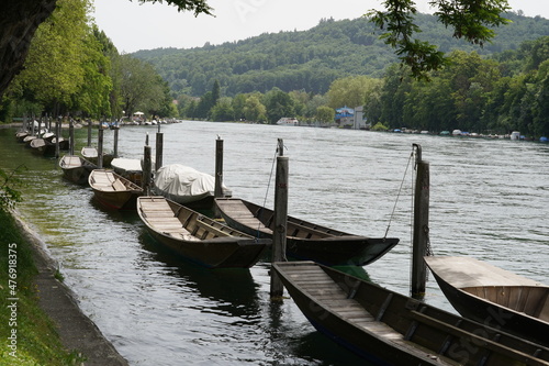 Wooden boats called Weidling in German language moored in a row along riverbank on Rhine river in Schaffhausen, Switzerland. Some of them are covered with tarpaulin. photo