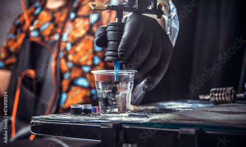 Obraz na plátně Hand of professional tattooer with a tattoo gun.