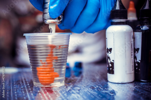 Obraz na plátně Hand of a tattooer, holding a tattoo device.