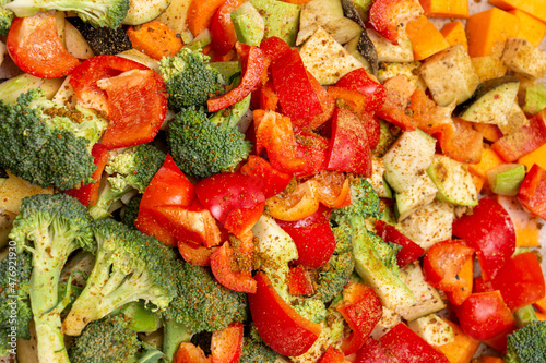 An original background of finely chopped and seasoned vegetables before baking in the oven. Potatoes, bell peppers, squash, pumpkin and broccoli. Healthy food close-up